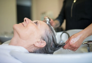 Senior woman relaxing in a salon chair while her hair is being washed by a stylist at a wash station